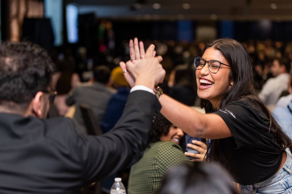 Two AMA Collegiate Chapter Members celebrating a victory with a high five at the International Collegiate Conference