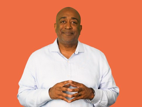 Man in white shirt standing against orange background