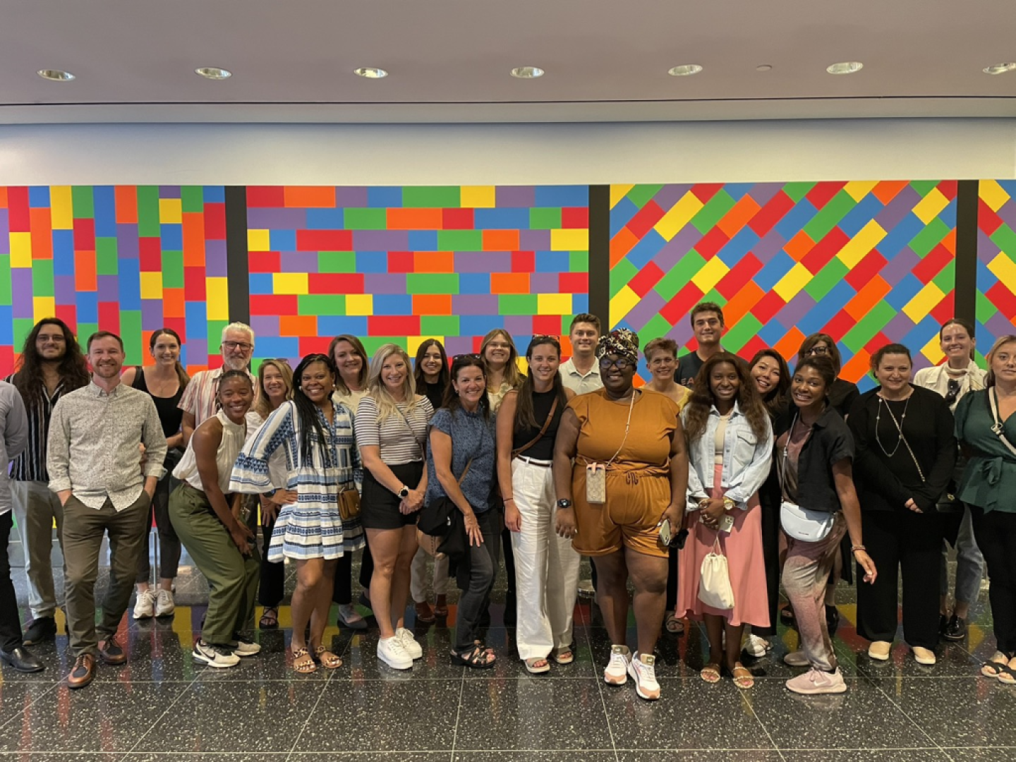 Marketing professionals stand in front of a colorful image during a break from an AMA marketing bootcamp event. 