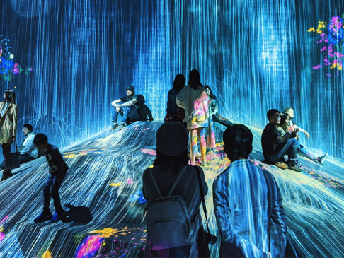 Picture of an art instillation that looks like light is pouring down like rain on people enjoying the experience